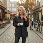 WARM IMPRESSIONS BUTTON DOWN stylish shacket in black with woman holding a cup in a cozy outdoor setting.
