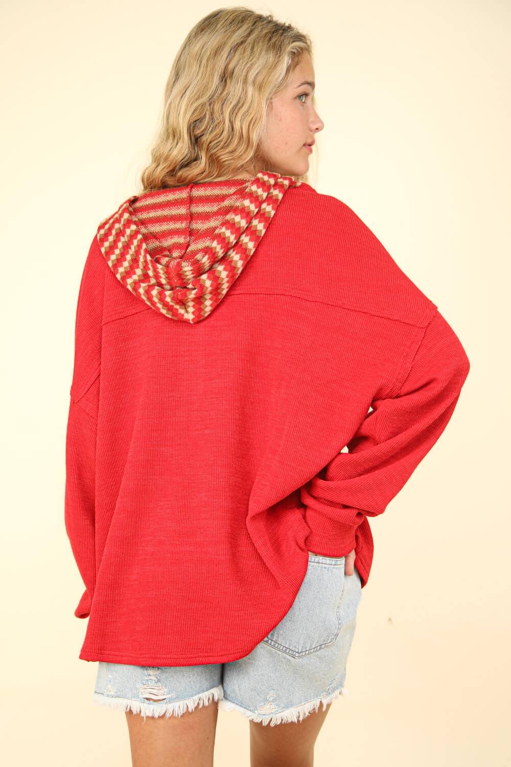 Model showcasing the back view of the oversized red contrast hoodie with a striped hood and loose fit, perfect for casual wear.