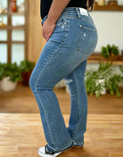 Plus size Judy Blue Irena Bootcut jeans with distressed detailing, showing a side view on a model.