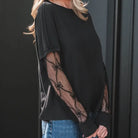 SIMPLY ENCHANTED TOP featuring a black tee with sheer lace mesh sleeves and bow-textured patchwork for a chic look.