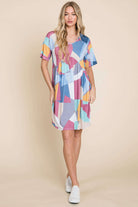 Model wearing DA1519 Shirred Waist Dress in colorful geometric print, featured with rounded neckline and mid-thigh length.