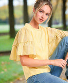 Model wearing Ruffled Breeze lemon cotton top with ruffle sleeves and button detail, paired with denim jeans.