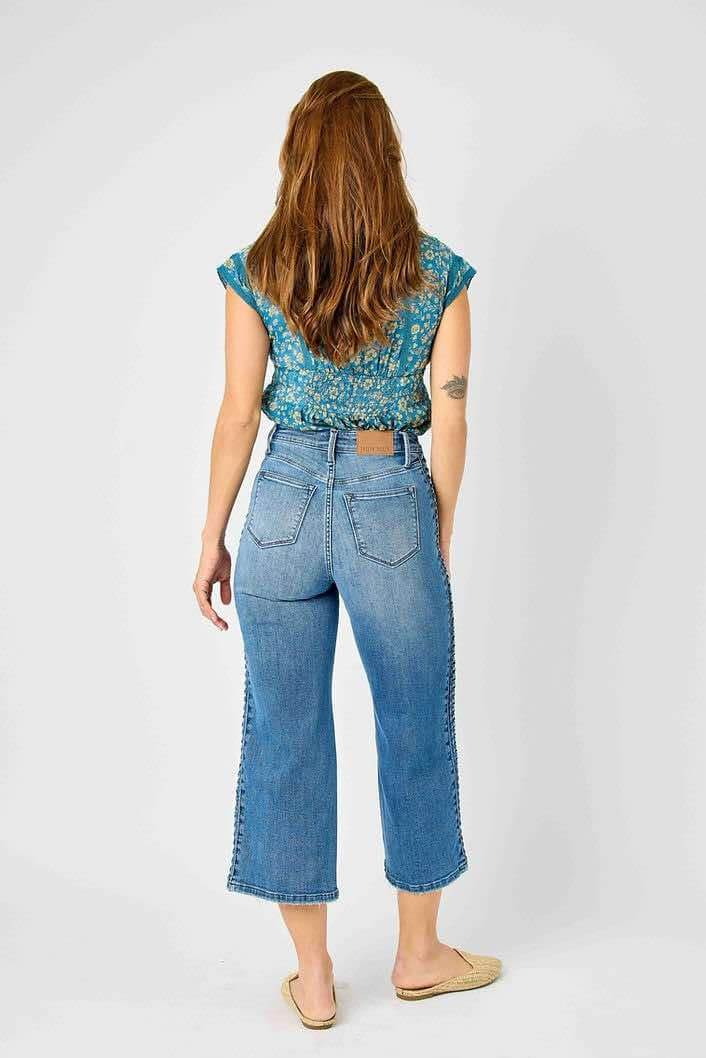 Woman wearing Judy Blue Braided Betty Jeans with unique braided detail and wide leg fit, showcasing stylish and trendy denim design.