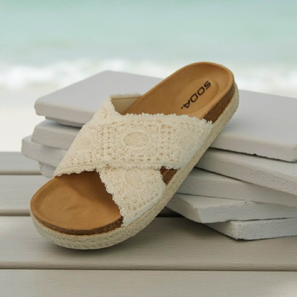 SEDINA CROCHET SANDALS - SODA on a wooden surface with a beach background, showcasing crochet knit and cork design.