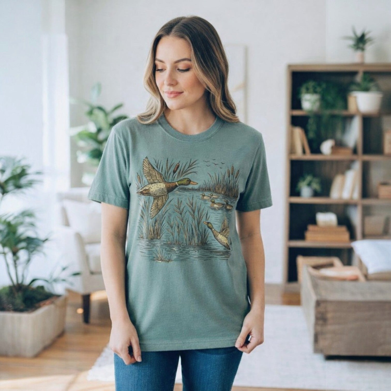 Woman wearing the TAKE FLIGHT TEE - The Lattimore Claim with detailed waterfowl graphic in a nature-inspired setting.