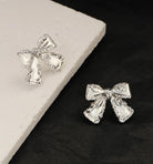 SILVER BOW Stud Earrings from the Vivian-Lu collection, featuring an elegant bow design on a textured surface.