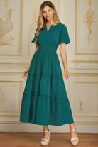 Teal green She+Sky Fleeting Moment dress with v-neck, tiered pintucks, elastic waist, side pockets, modeled by woman indoors.