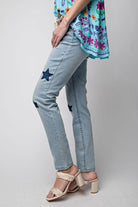 Woman wearing Star Walk Jeans by Easel with star patches and a floral top, showcasing slim fit and stretch denim.