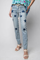 Woman wearing Star Walk Jeans with star patches and slim fit design from Easel, paired with a floral top and sandals.