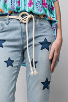 Woman wearing Star Walk Jeans with star patches and a floral top, showcasing slim fit and stylish denim design with rope belt.