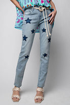 Woman wearing Star Walk Jeans by Easel with star patches, 5-pocket design, button closure, and zip fly, paired with a floral top and sandals.