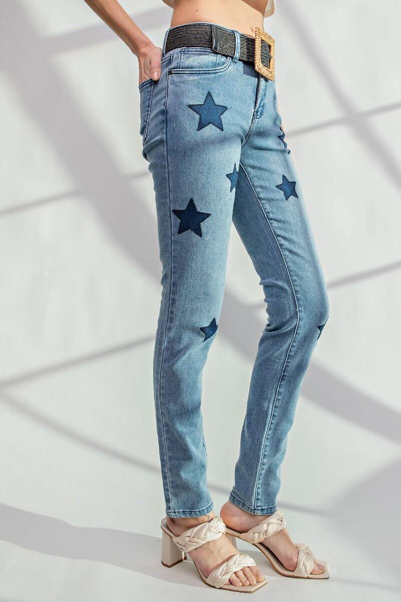 Star Walk Jeans by Easel with star patch details, slim fit, soft stretchy denim, model wearing sandals, side view.