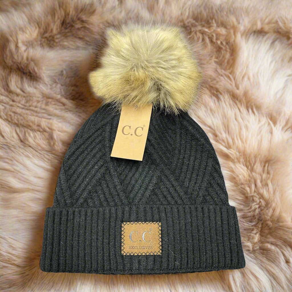 Warm Angle Beanie by C.C. in black with faux fur pom pom, featuring a diagonal pattern and cozy snug fit.