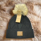 Warm Angle Beanie by C.C. in black with faux fur pom pom, featuring a diagonal pattern and cozy snug fit.