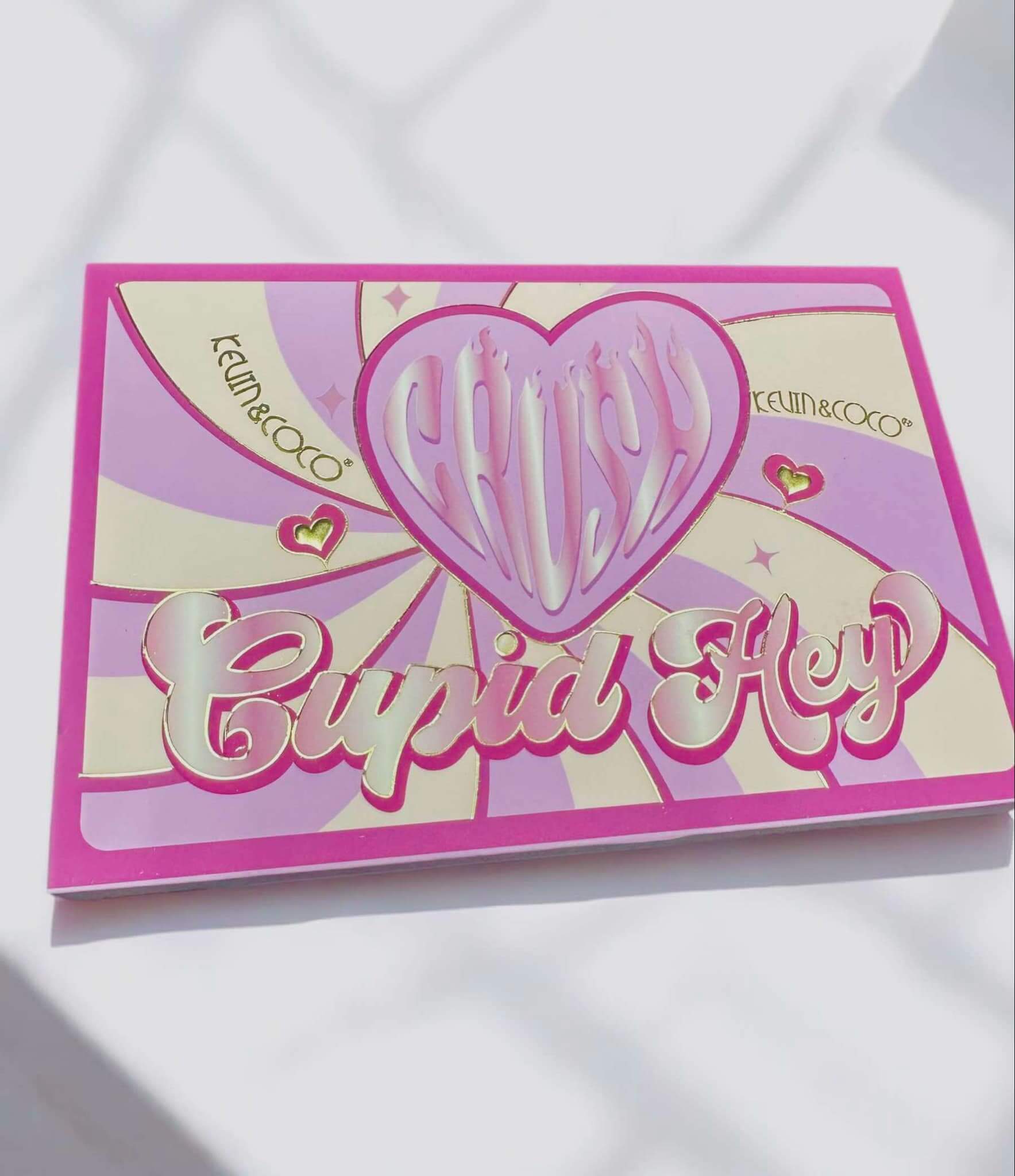 Cupid Hey Eyeshadow Palette by Kevin & Coco featuring vibrant pink packaging with a heart design. Perfect for a flirty look.