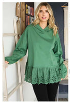 Woman wearing green Cotton Bleu Adventure Awaits hoodie with eyelet ruffle and long sleeves, standing by wooden ladder indoors.