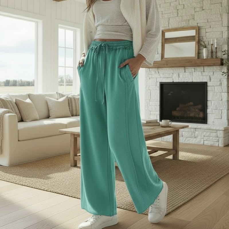 AQUA DRIFT WIDE LEG PANTS in a soft sea green color, featuring a stretchy waistband and styled in a cozy living room setting.