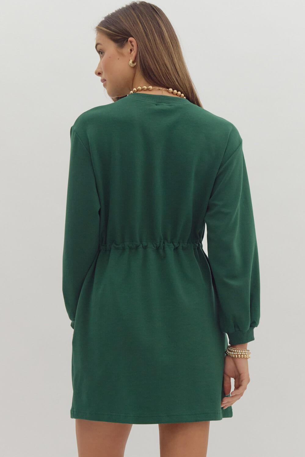 Woman wearing EVERGREEN BREEZE dress with drawstring waist in dark green, showcasing back view and crewneck style.