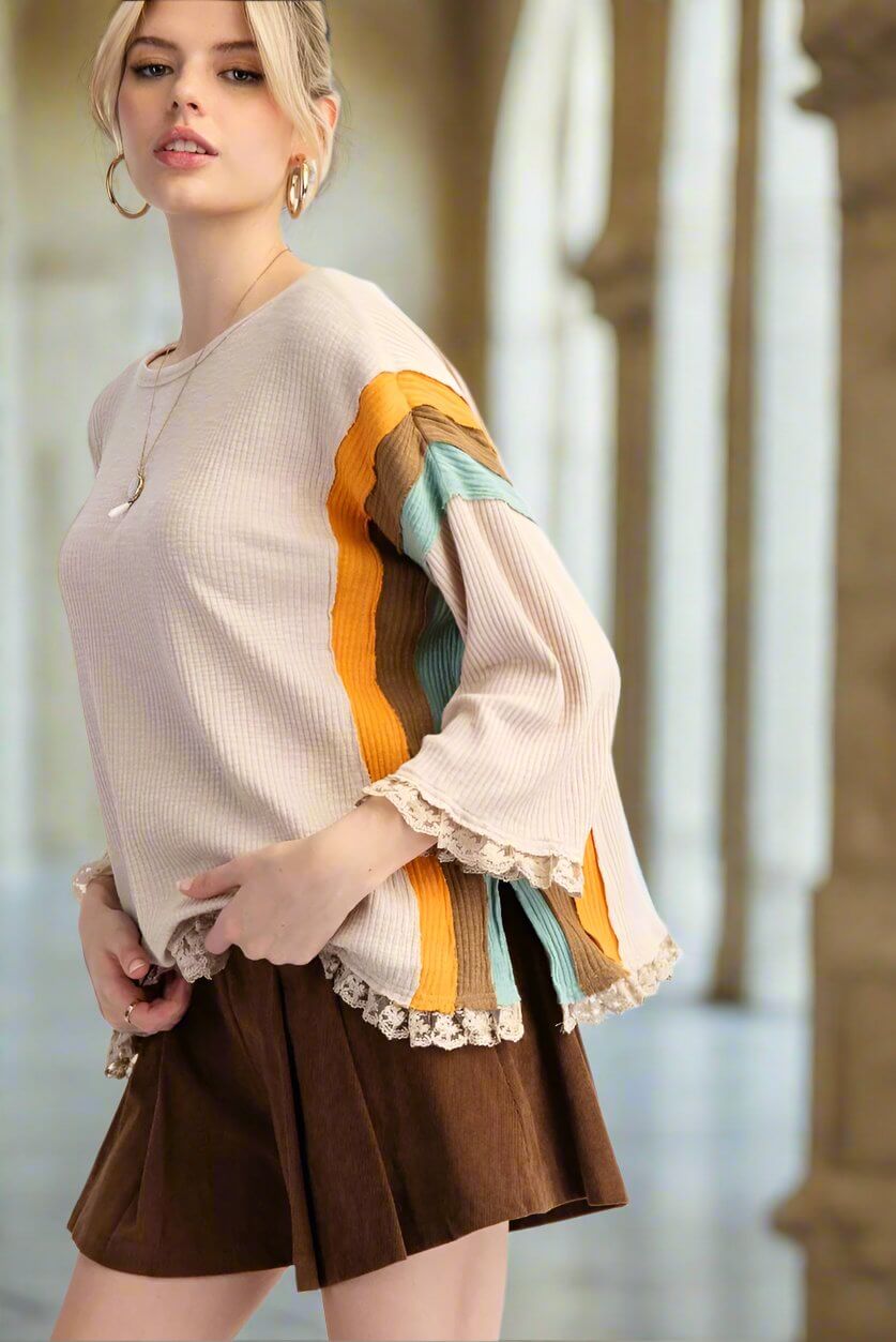 Model wearing KEEP THE FAITH top by Easel with striped sleeves and lace hem, paired with a brown skirt in a stylish setting.