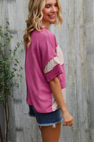 Woman in fuchsia floral wavy rib pullover and denim shorts, showcasing trendy color block style.