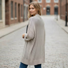 Woman wearing BAREFOOT MORNINGS CARDIGAN, standing casually in a cobblestone street, showcasing its relaxed style.