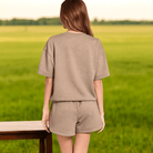 Back view of a woman in a comfy ENERGY TO SPARE 2 Piece Set, featuring a relaxed round-neck top and dolphin shorts.