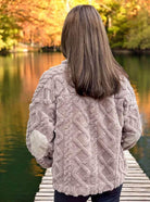 Woman wearing a charcoal cable-pattern TEDDY BEAR SHERPA by Very J, featuring elbow corduroy patches, standing on a lakeside dock in autumn.