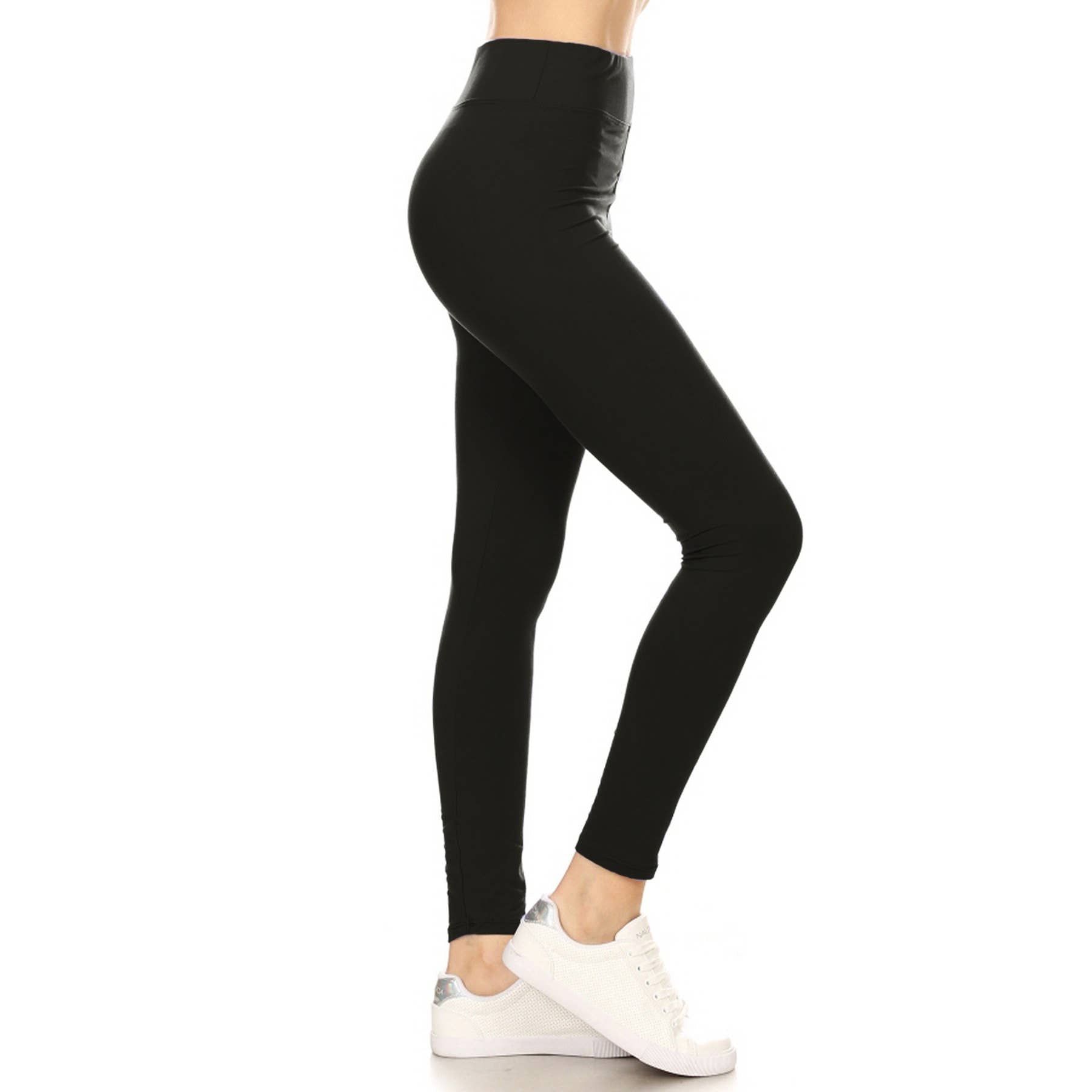 Black buttery soft solid leggings with high waist and yoga style waistband, side view on model wearing white sneakers.