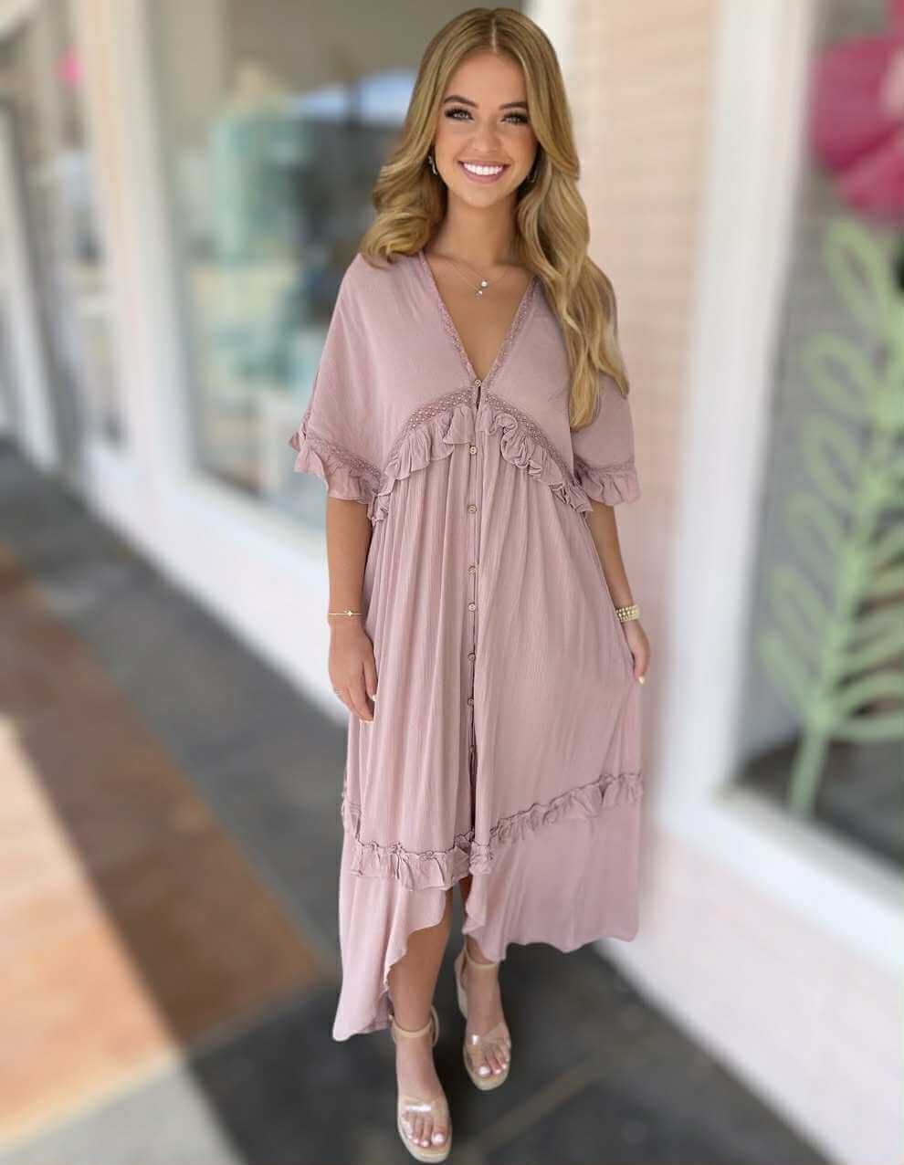 Model wearing blush Ever After Maxi Dress featuring ruffles and a soft tie-back detail, ideal for romantic outings.