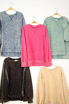 Collection of oversized crewneck sweatshirts in various colors, including pink, displayed on hangers for a trendy look.