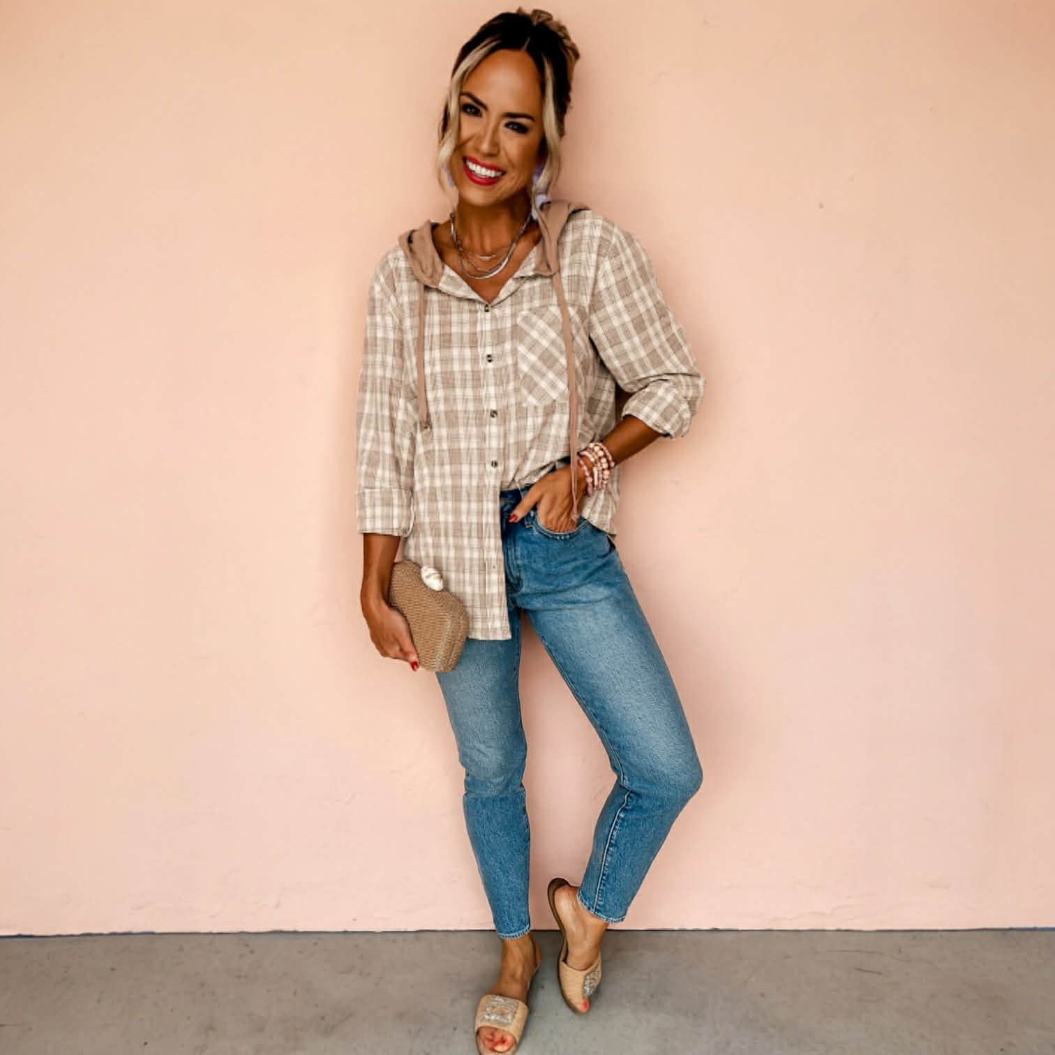 Woman modeling DRIFTWOOD DAYS BUTTON DOWN khaki checkered print shacket with jeans, smiling against a pink background.