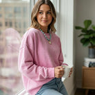Model wearing a COMFORT CRUSH CREWNECK in bright pink, holding a cup, showcasing the cozy style and mineral wash finish.