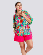 Curvy woman wearing The Perfect Blend Top with vibrant floral design and fuchsia shorts, perfect for any occasion.