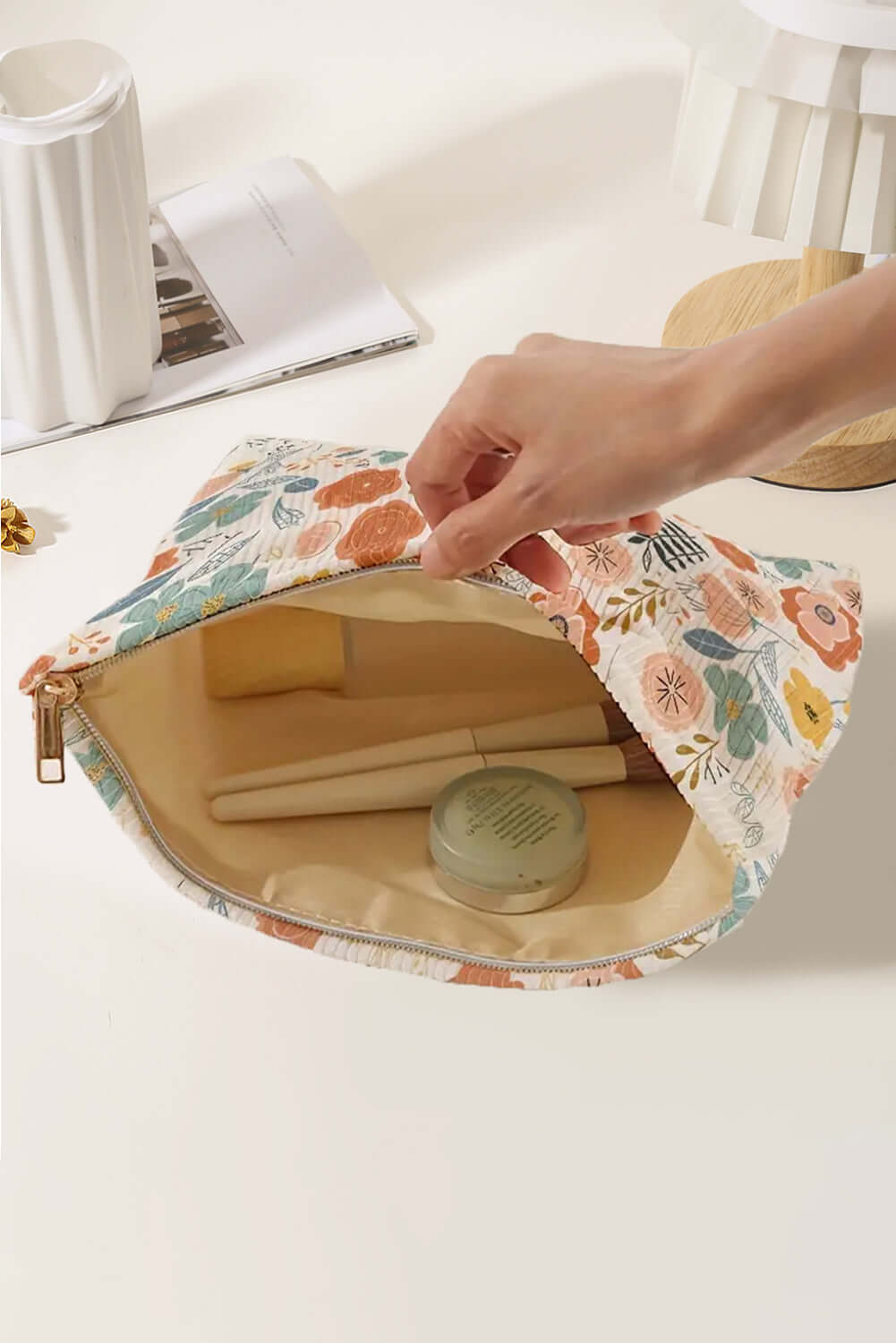 Open Cottage Carry Cosmetic Bag showcasing floral print, holding beauty items on a clean surface.