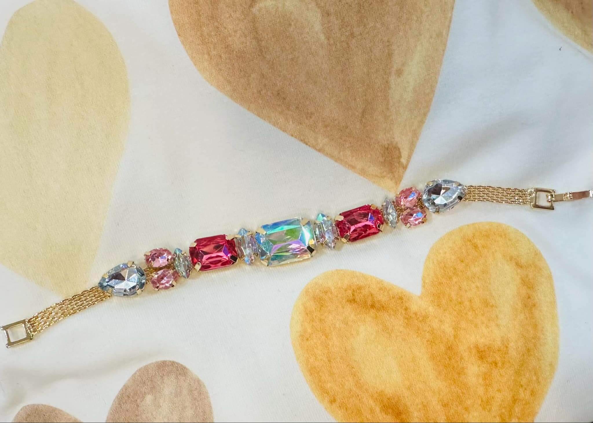 Sparkle Theory Bracelet featuring oversized gems in pink, crystal blue, and iridescent opal tones on a gold-tone chain.