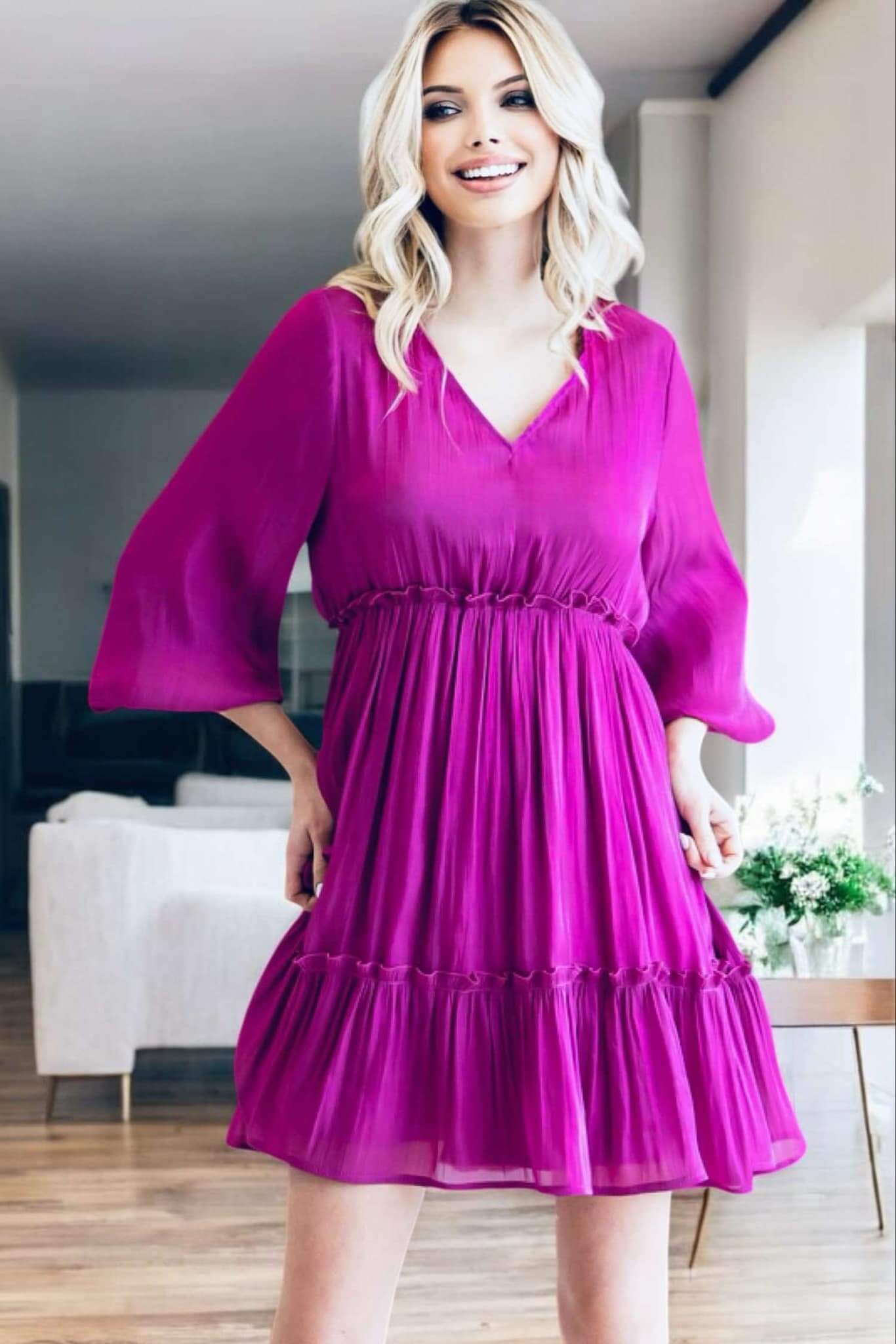 Woman wearing the Bermuda Beauty Dress in jewel tone magenta with v-neckline and balloon sleeves, perfect for any occasion.