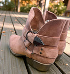 VERY G CAROLINA ANKLE BOOT in rose tan suede with side buckle and zip design on a wooden surface.
