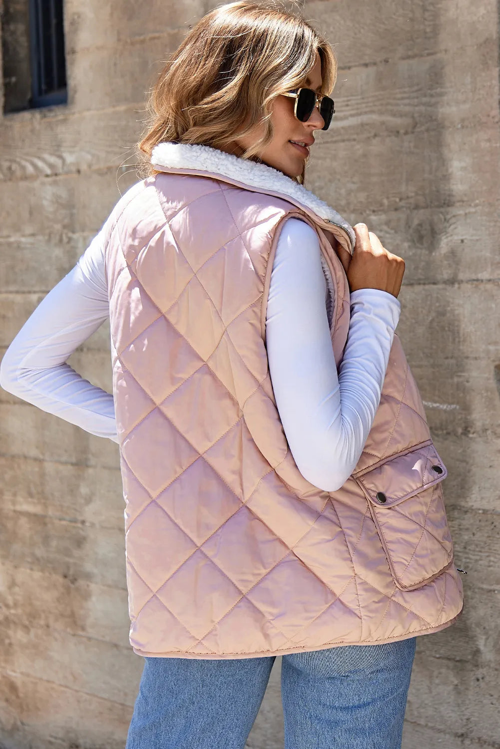 Woman wearing a REVERSIBLE RETREAT VEST! in pink sherpa lined quilted design.