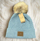 Light blue beanie by C.C. with faux fur pom pom and diagonal pattern on a white background.