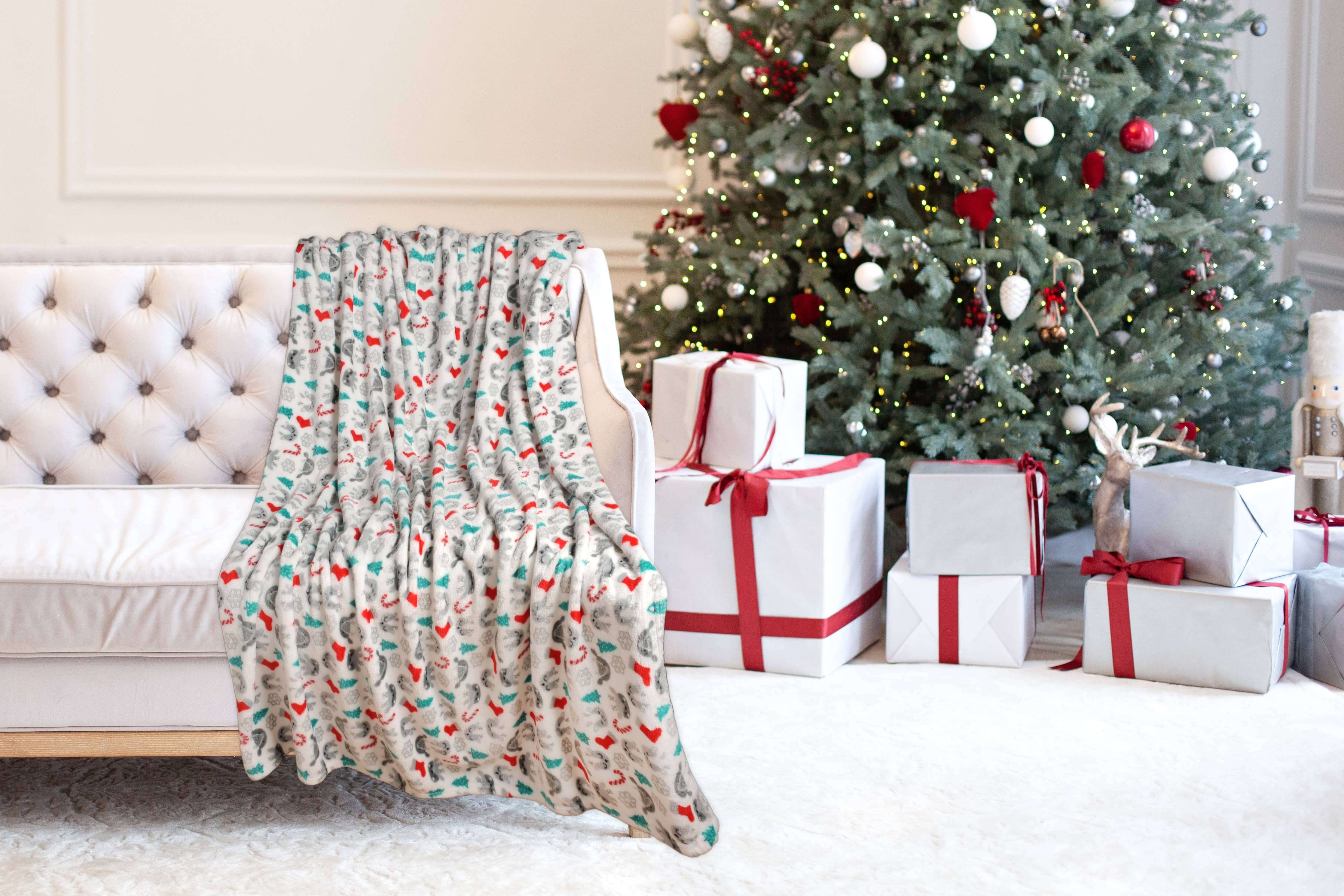 Christmas Cheer Plush Throw Blanket on sofa, festive room with Christmas tree and gifts, cozy holiday decor by Kathy Ireland