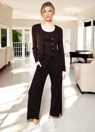 Woman modeling black Easy Living ribbed pants and cardigan in a stylish interior, highlighting trendy fashion and comfort.