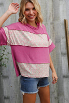 Model wearing fuchsia floral wavy rib pullover with shorts against wooden backdrop, showcasing casual chic style.