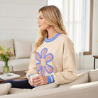 DAYDREAM BELIEVER - Sage + Fig (beige) crew neck pullover with daisy appliqué, styled cozy on a couch.
