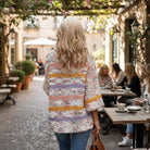 A woman wearing the EASY LIKE SUNDAY SWEATER in a cafe setting, exuding relaxed style and comfort.