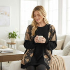 A woman enjoying a cup of coffee, wearing the HOMETOWN HARMONY TOP - Heimish in a cozy living room setting.
