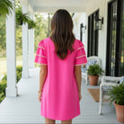 Model wearing the Kersten Ric Rac Dress, Hot Pink, showcasing the back view with layered ruffle sleeves.