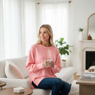 Woman in SOFT INTENTIONS Pullover by Zenana (soft pink) enjoying coffee in a cozy living room.