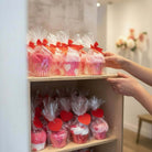 Too Cute to Eat Valentine Sock Cupcakes in gift wrap with red bows and heart tags arranged on a shelf.