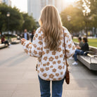 HONEY BLOSSOM SHERPA JACKET on a woman walking in a park, featuring a cute flower pattern in light French beige.