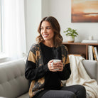 Woman enjoying coffee in cozy setting wearing HOMETOWN HARMONY TOP - Heimish, featuring floral color block design.